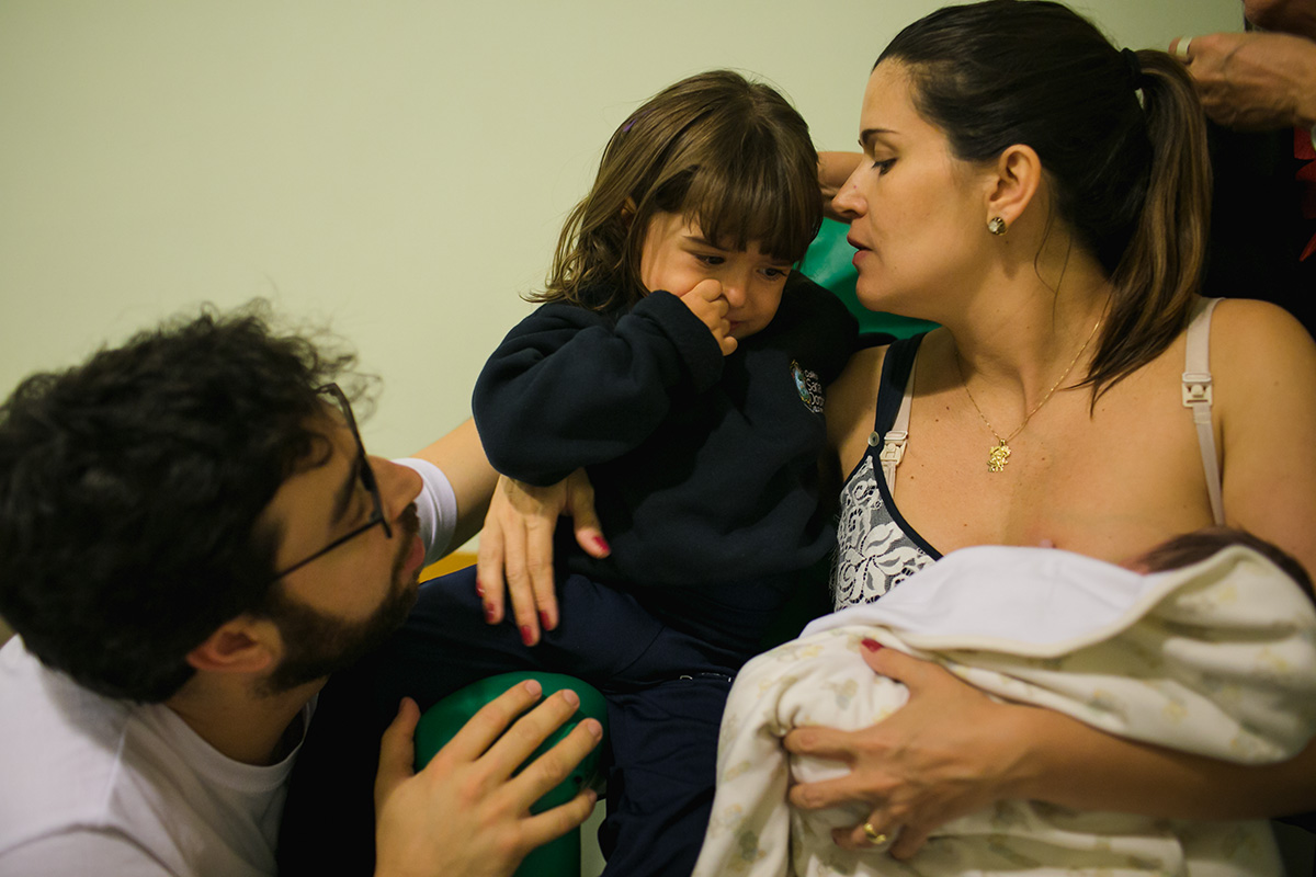 pais consolam filha mais velha que está com ciúmes do irmão que acaba de nascer