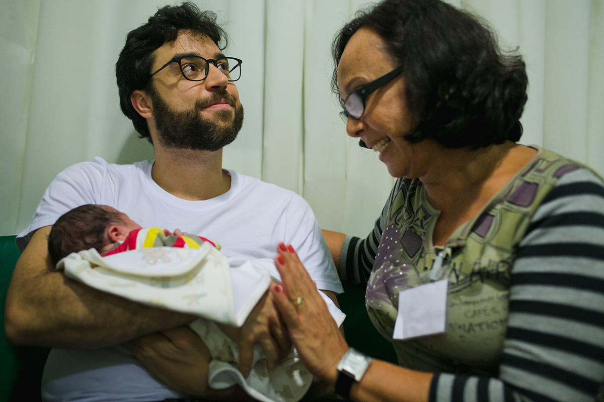 avó dá carinho ao neto que está no colo do seu filho