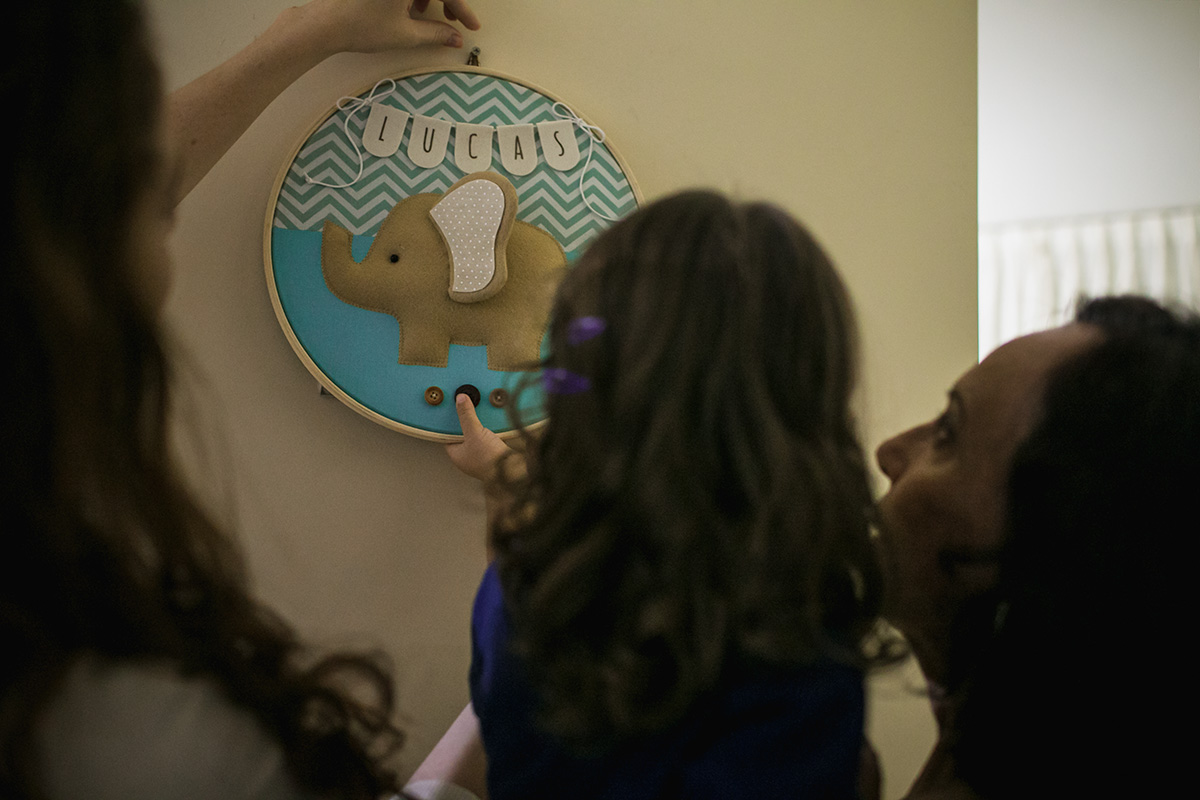 irmã coloca enfeite na porta do quarto da maternidade com o nome do irmão em foto feita por adrianacostafotos