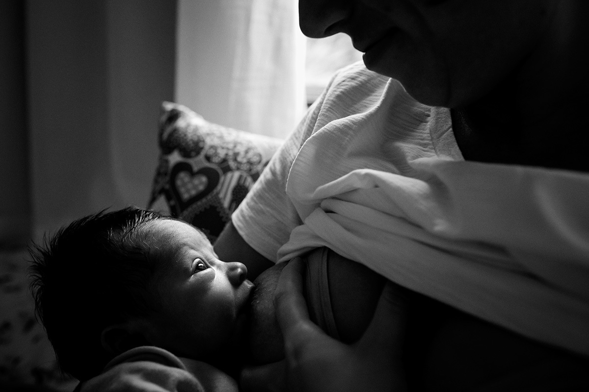 bebê de poucos dias olhando para o rosto da mãe enquanto amamenta, por adrianacostafotos