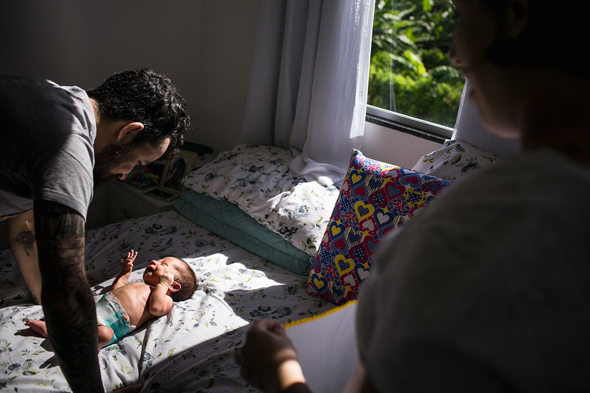 pai e mãe observando seu bebê tomar banho de sol