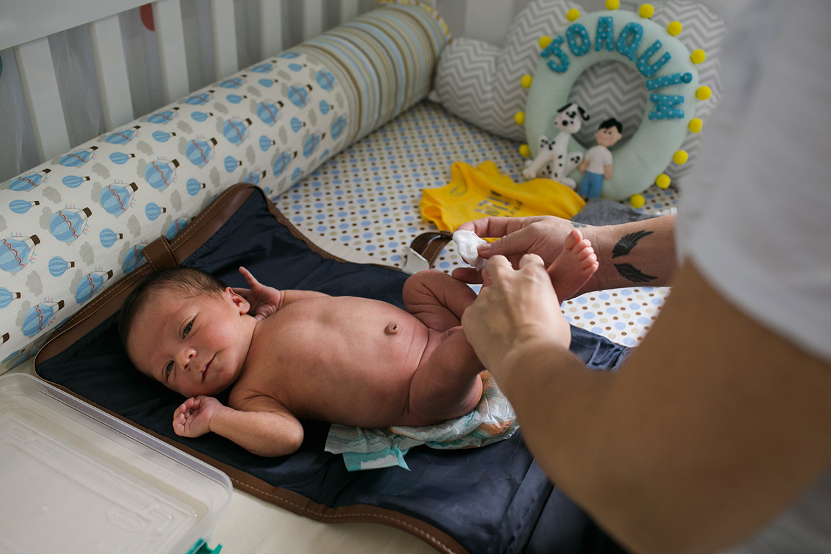 mãe preparando seu bebê para o banho em uma foto feita por Adriana Costa