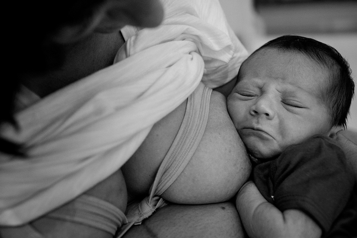 Bebê fazendo carinha de choro no colo da mãe em uma fotografia feita por Adriana Costa