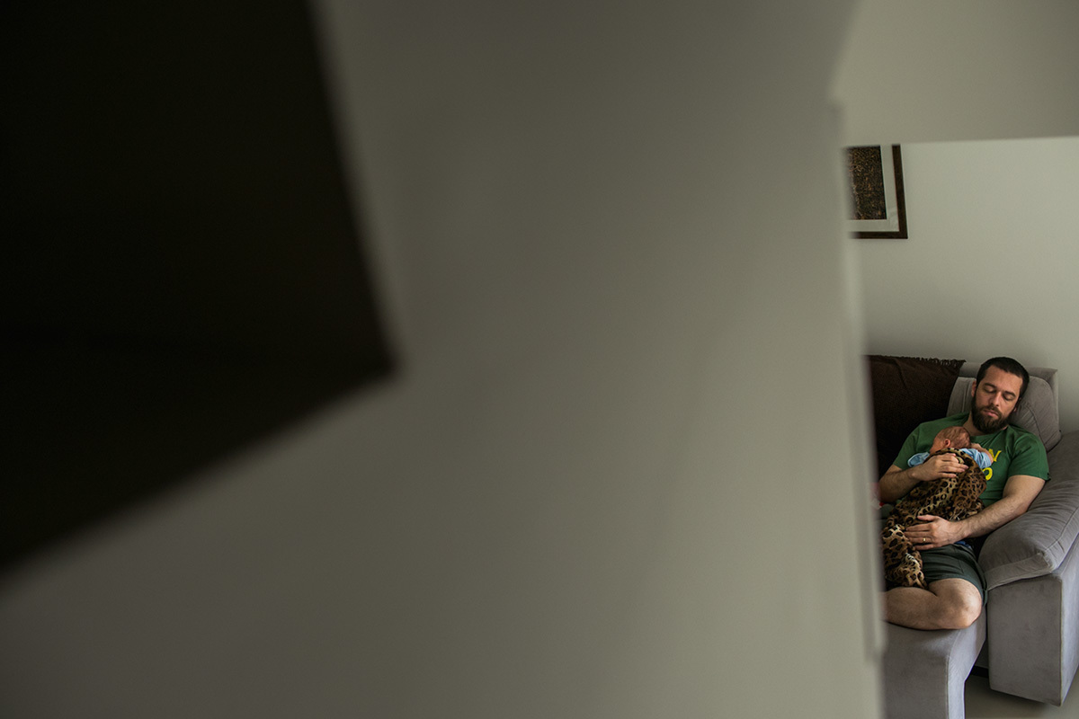 pai cochilando no sofá com seu bebê na barriga por Adriana Costa