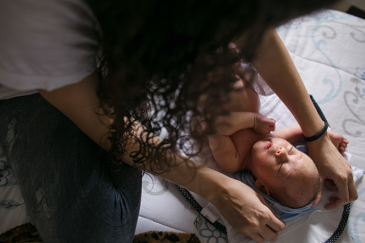 mãe tirando a blusa do seu bebê