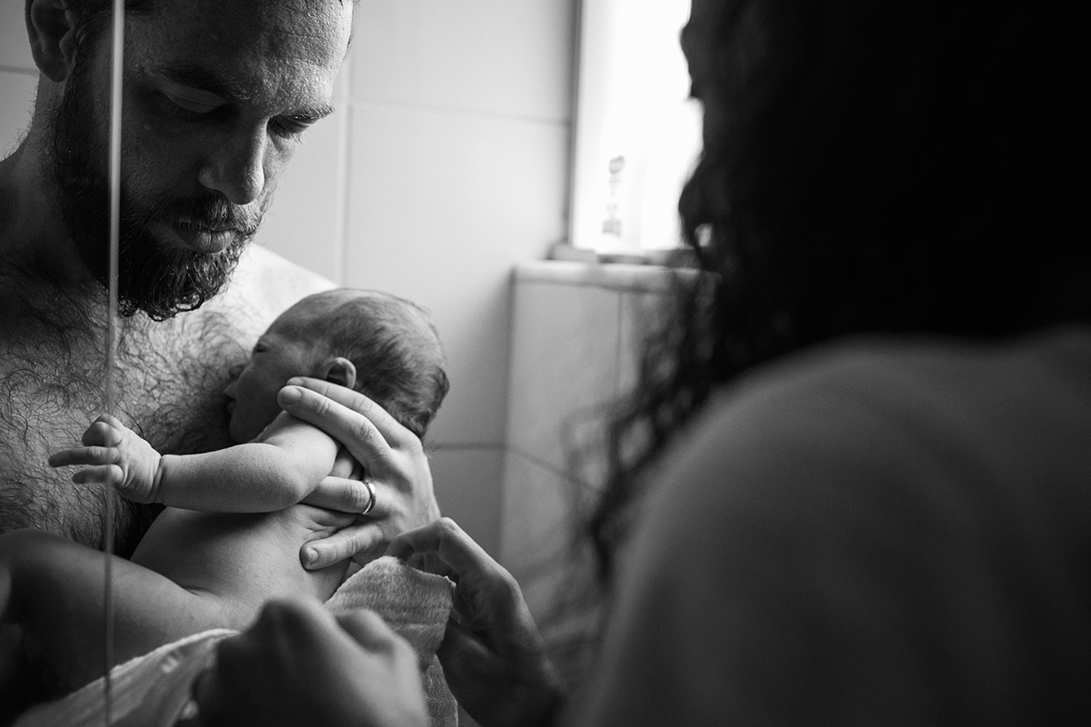 mãe passando seu filho para o pai no chuveiro, por adrianacostafotos