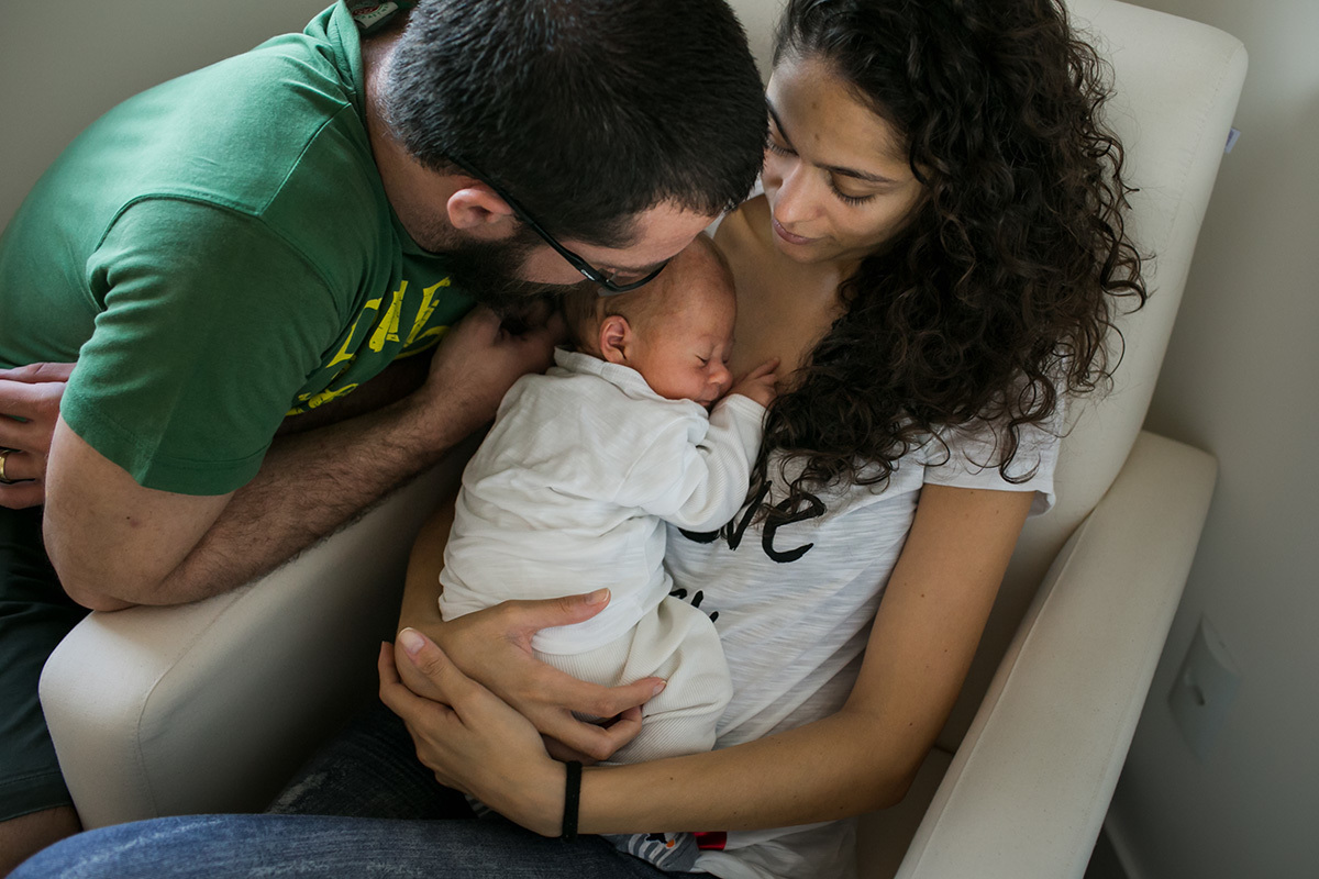 pai e mãe admirando seu bebê