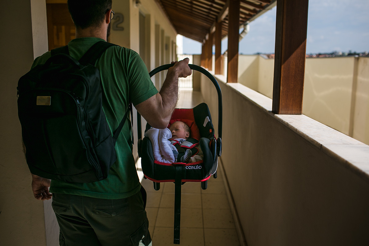 pai levando seu filho no bebê conforto para sair, por Adriana Costa