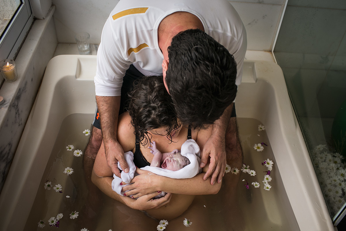 foto de Adriana Costa dos pais admirando a filha que acabou de nascer em sua própria casa