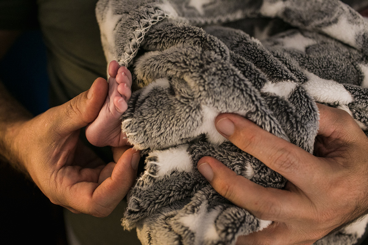 foto mostrando a comparação do tamanho da mão do pai com o pé de sua filha que acabou de nascer, por Adriana Costa