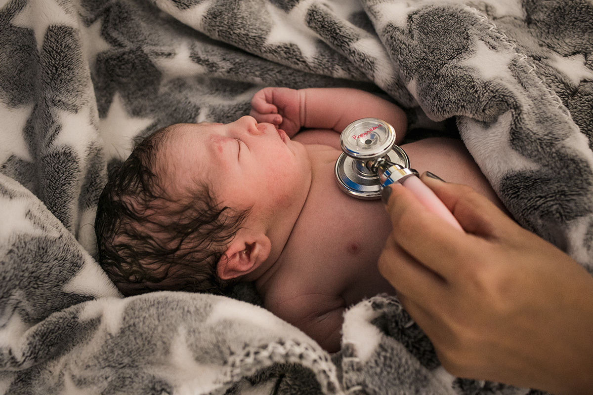 Bebê sendo avaliado após um parto domiciliar em foto de Adriana Costa