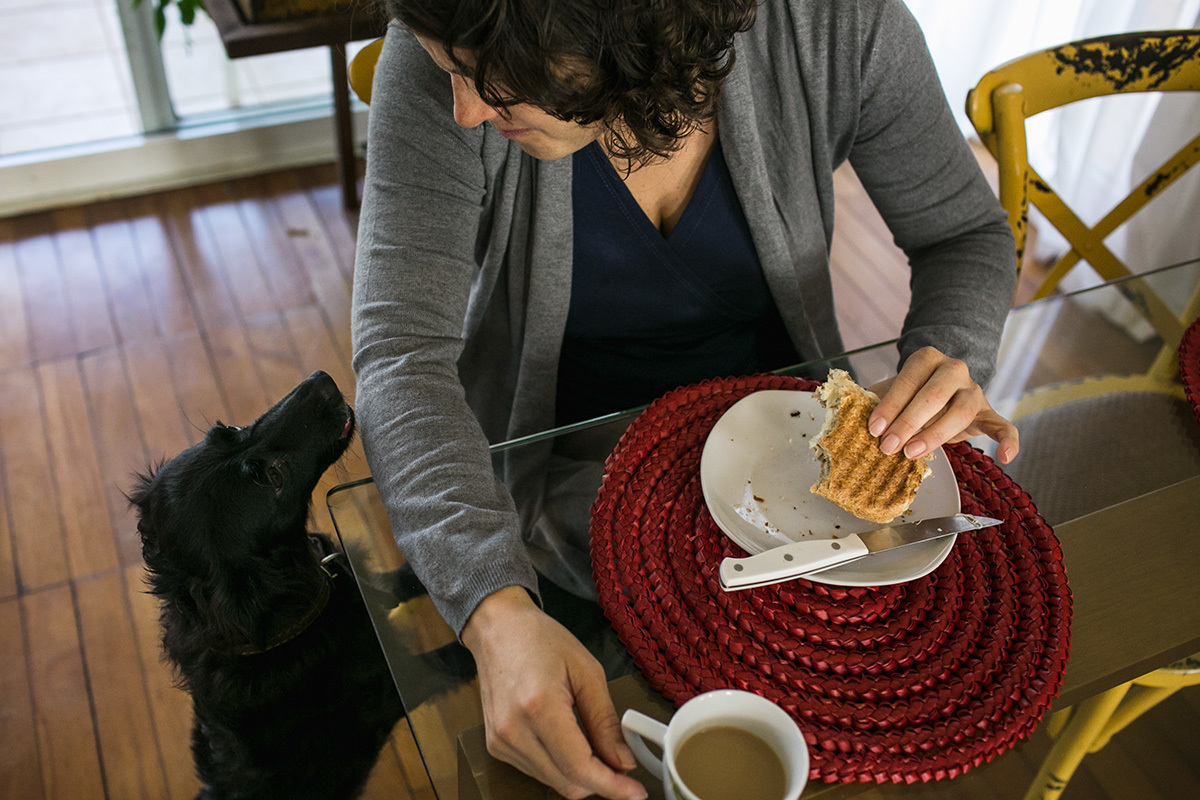 mãe tomando café da manhã com seu cão olhando, por Adriana Costa