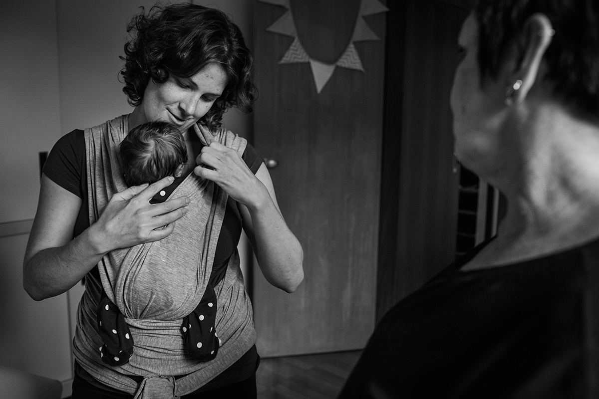 mãe colocando seu bebê no sling wrap, por Adriana Costa