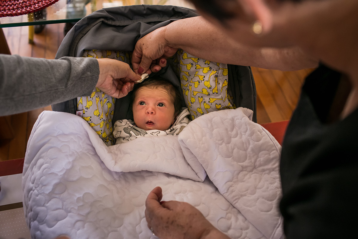 mãe e avó colocando um lacinho na bebê de poucos dias, por Adriana Costa
