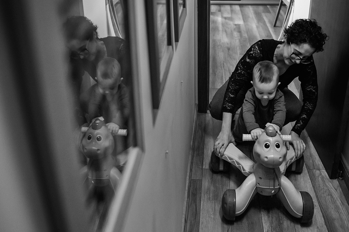 Foto de Adriana Costa da mãe e filho brincando no corredor da casa e seus reflexos no quadro