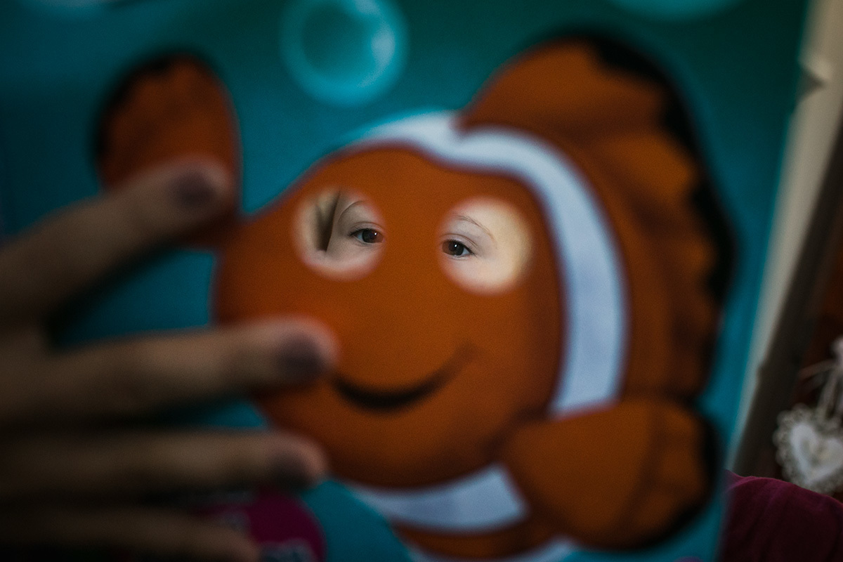 Adriana Costa fotografou o bebê vendo livro infantil através dos buracos da capa do livro