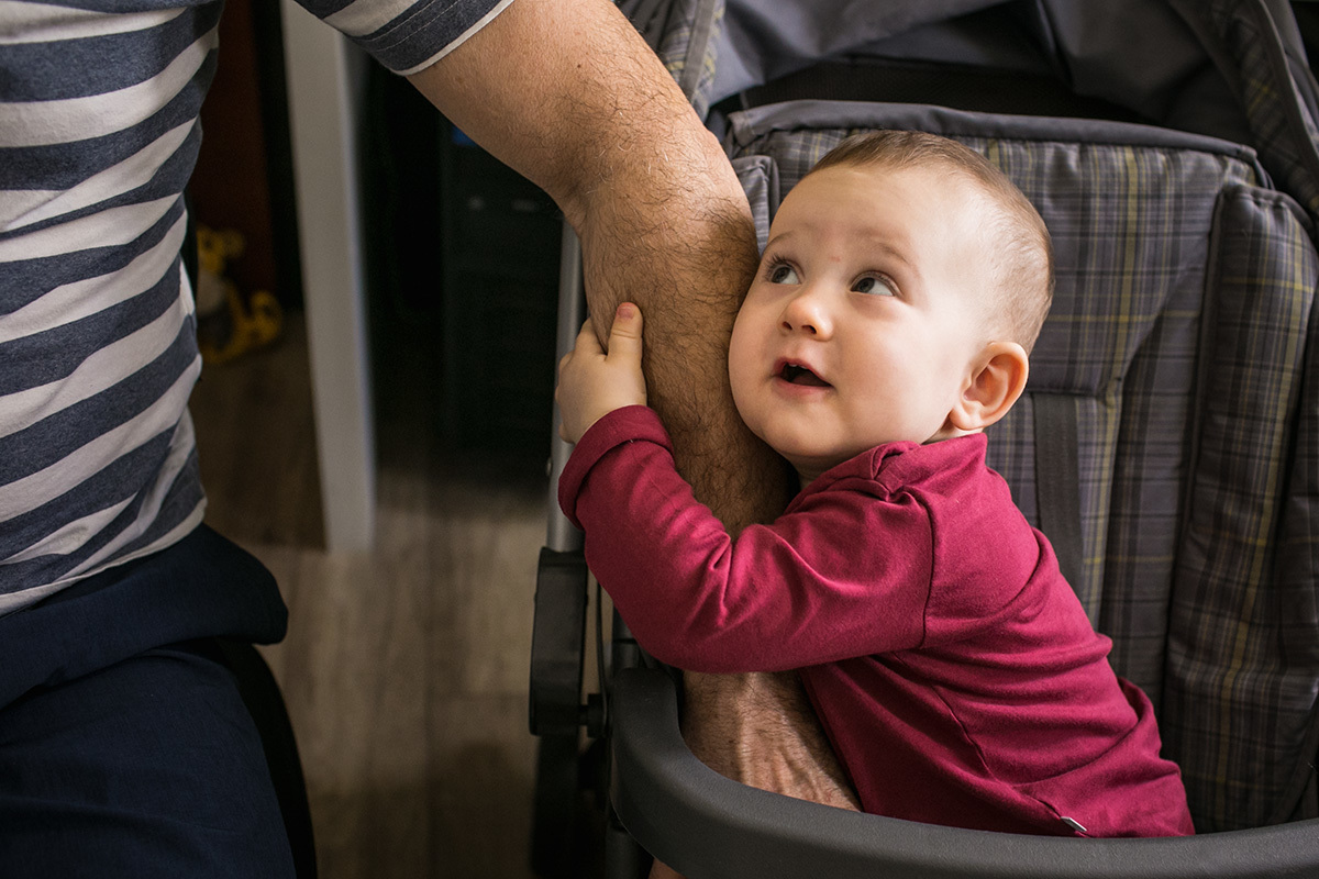 bebê agarrado ao braço do pai em foto de Adriana Costa