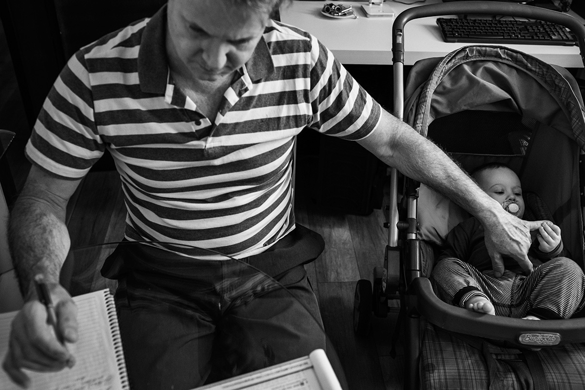 pai estudando e ao mesmo tempo ninando seu bebê em foto de Adriana Costa