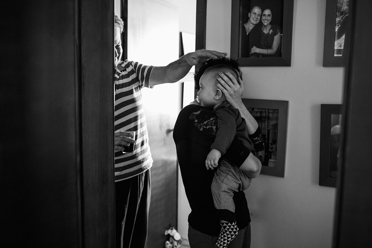 mãe levando seu bebê para dormir e pai se despedindo dele, por Adriana Costa