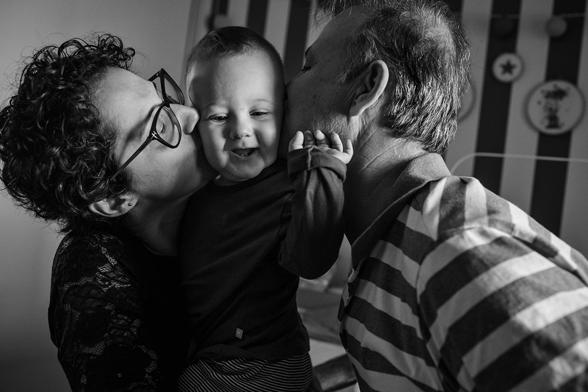 Pais dando beijo em seu bebê em foto de Adriana Costa