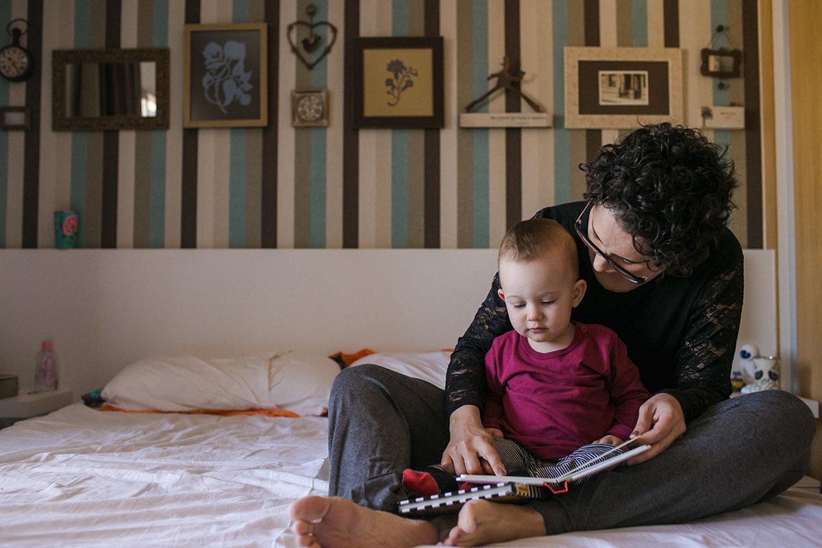 mãe e filho lendo o livros sobre a cama de casal, por adrianacostafotos