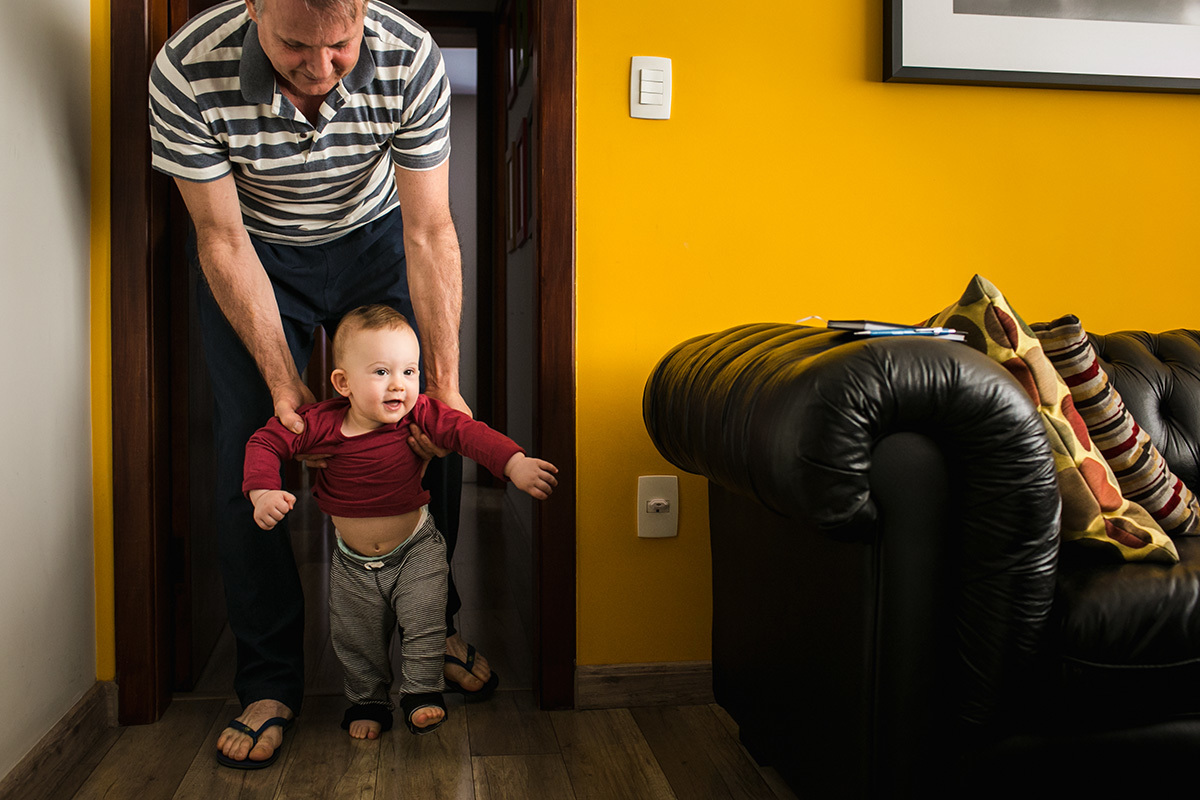 pai ajudando seu bebê a andar, em foto feita por Adriana Costa