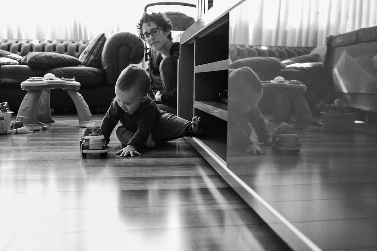 bebê engatinhando atrapalhado sob os cuidados da mãe, por Adriana Costa