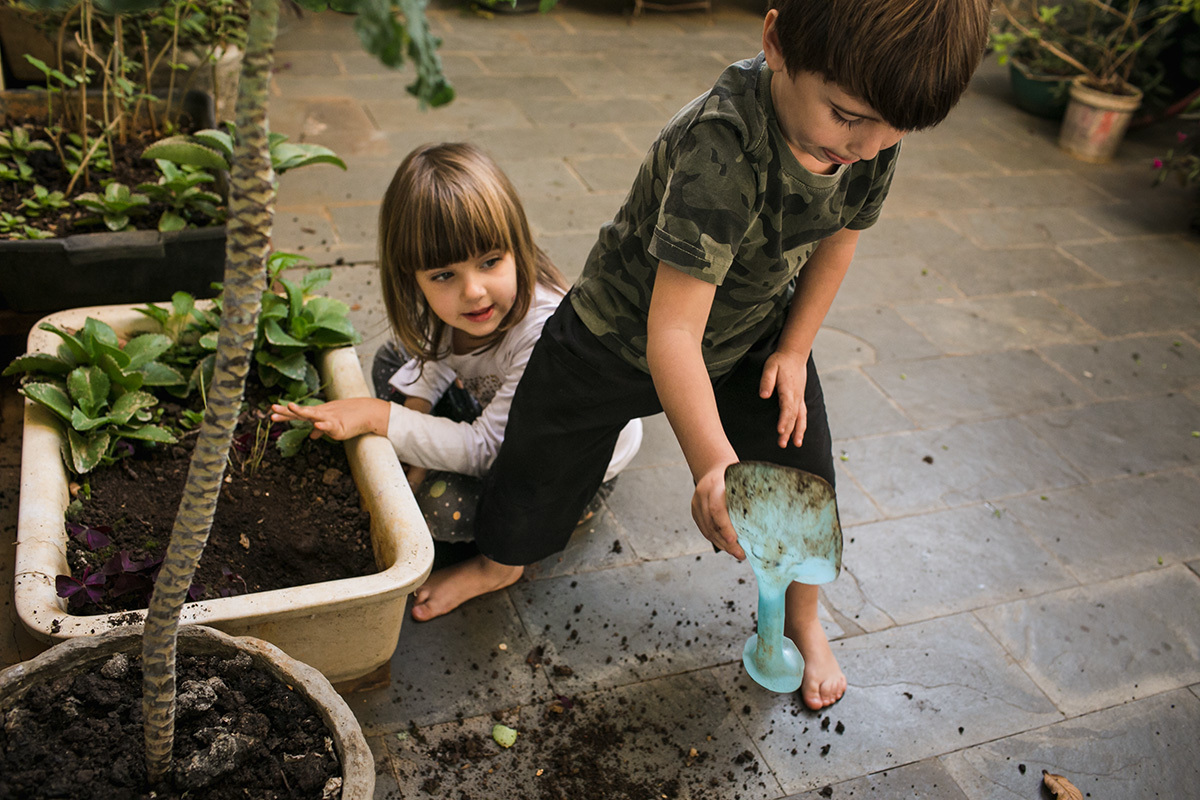 primos jogando a terra fora do vaso da avó em foto de Adriana Costa