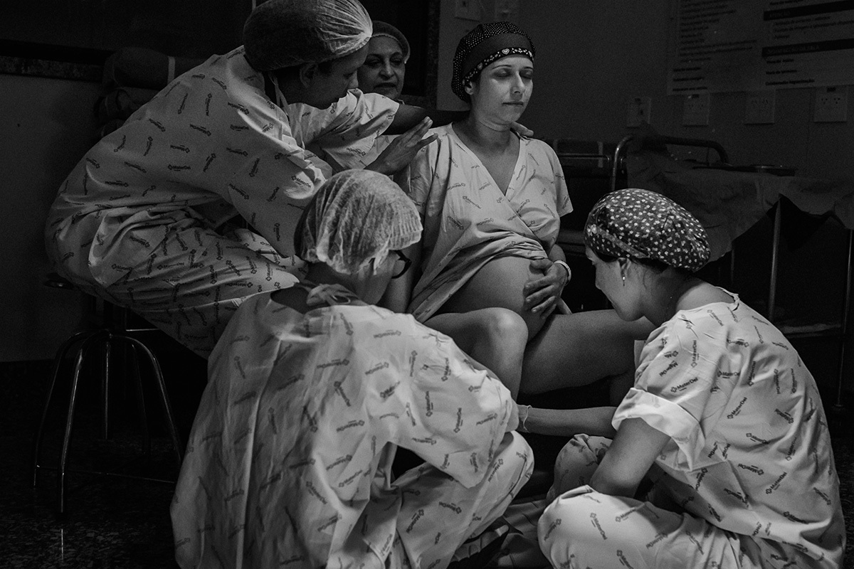 foto de Adriana Costa da gestante no banco de parto recebendo o apoio da doula, enfermeira obstétrica e médica obstetra do Instituto Nascer