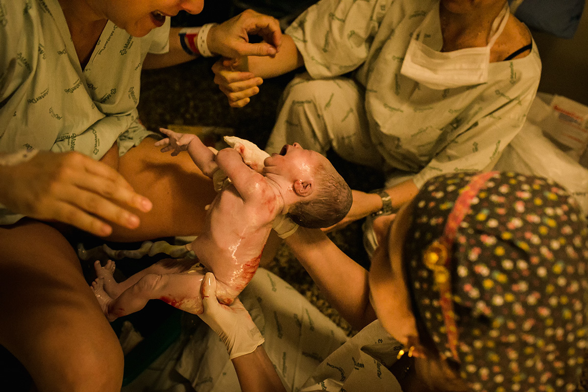 foto de Adriana costa do bebê nascendo com a mãe na banqueta de parto