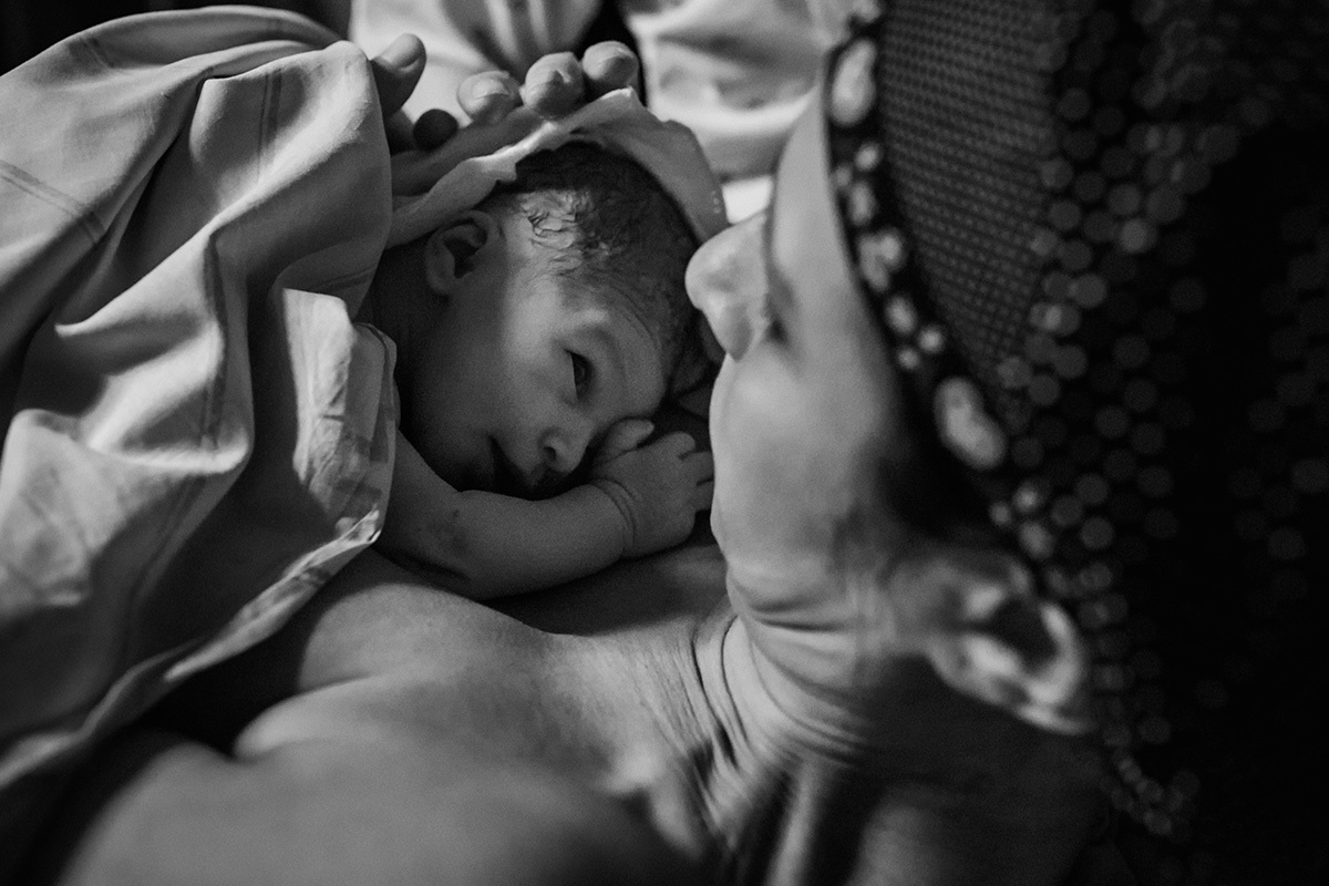 Bebê que acabou de nascer olha para sua mãe em foto de Adriana Costa