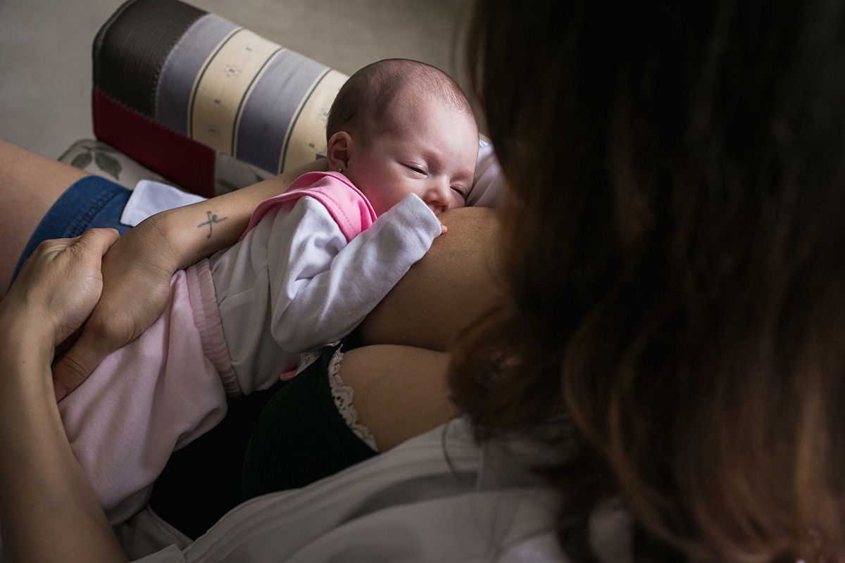 Bebê quase dormindo ao amamentar em foto feita por adrianacostafotos