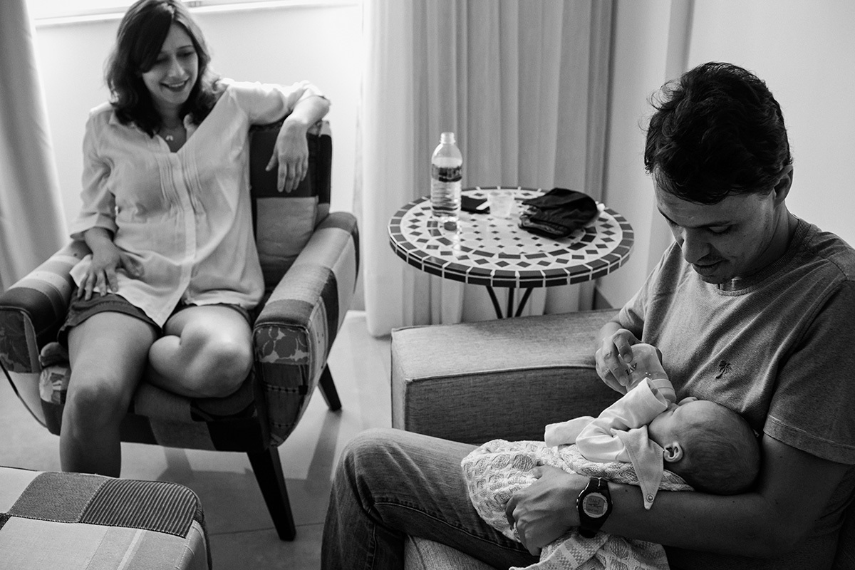 foto de Adriana Costa da esposa observando seu marido dar mamadeira para sua filha