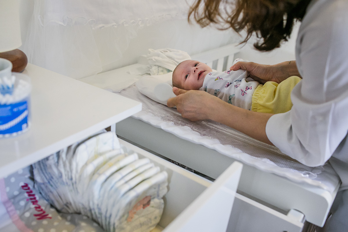 foto de Adriana Costa da mãe terminando de vestir sua bebê após o banho