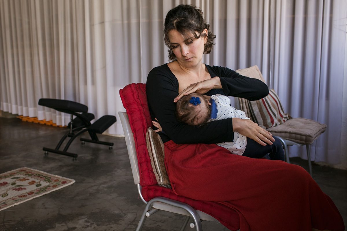 mãe fazendo carinho no bebê enquanto ela amamenta, por Adriana Costa