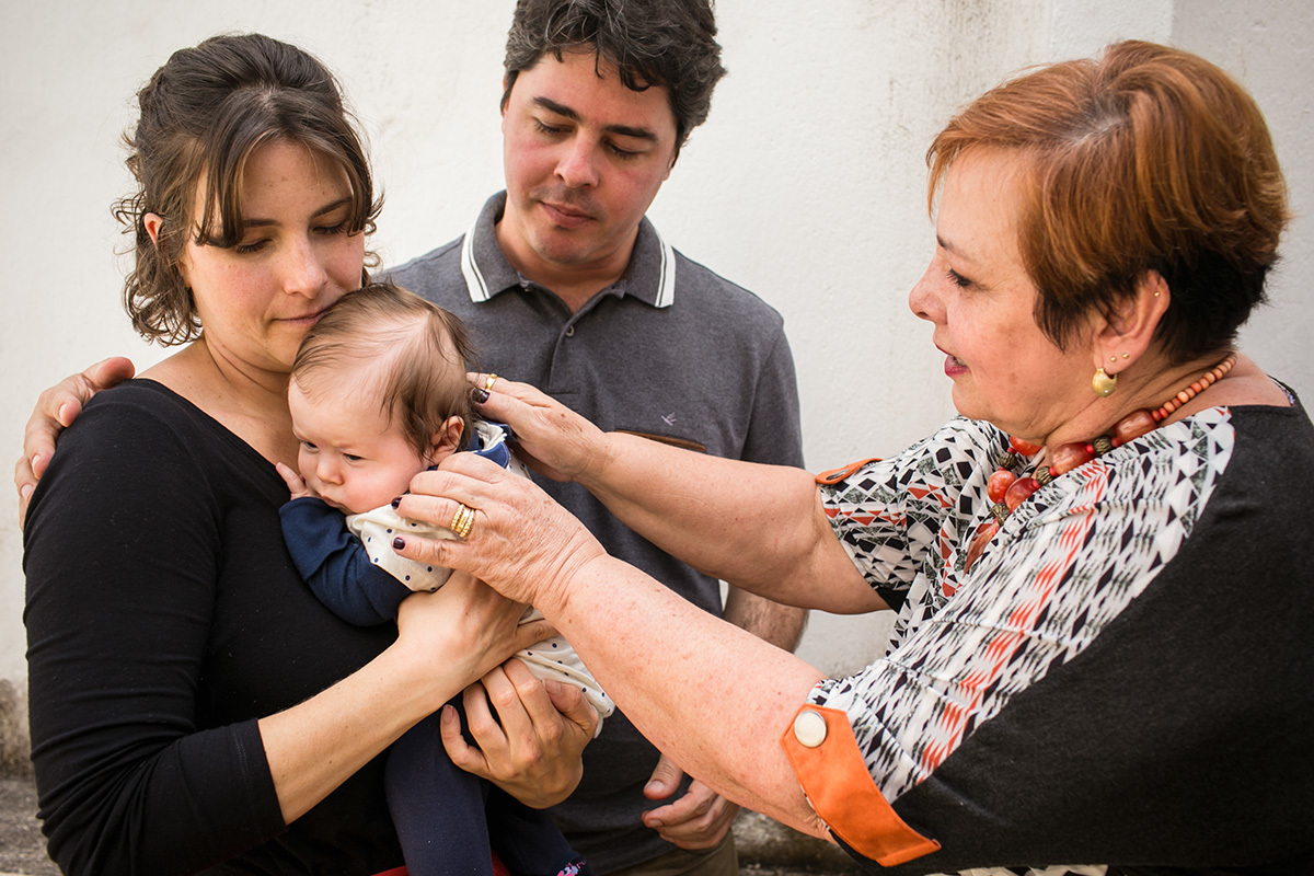 Avó passa para o colo dos pais sua neta