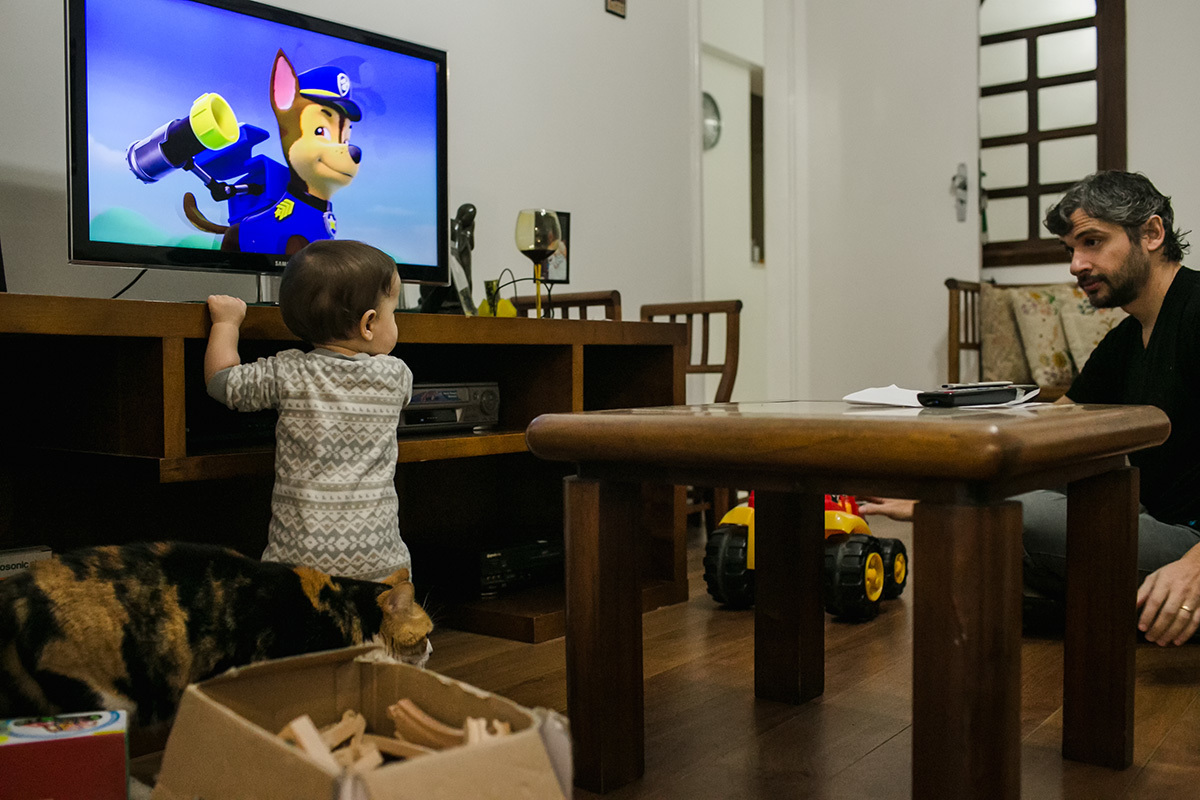 bebê assistindo TV com o pai e o seu gato