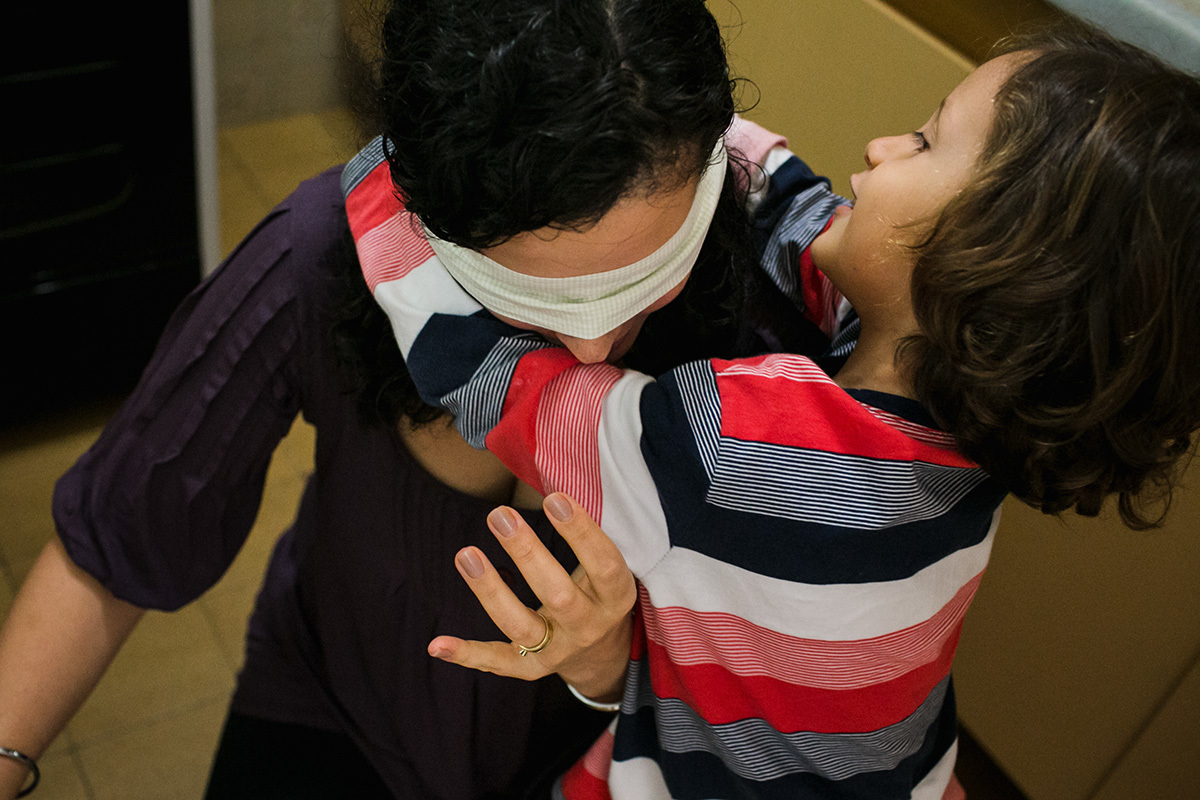 filho tentando amarrar a venda na mãe para lhe fazer uma surpresa