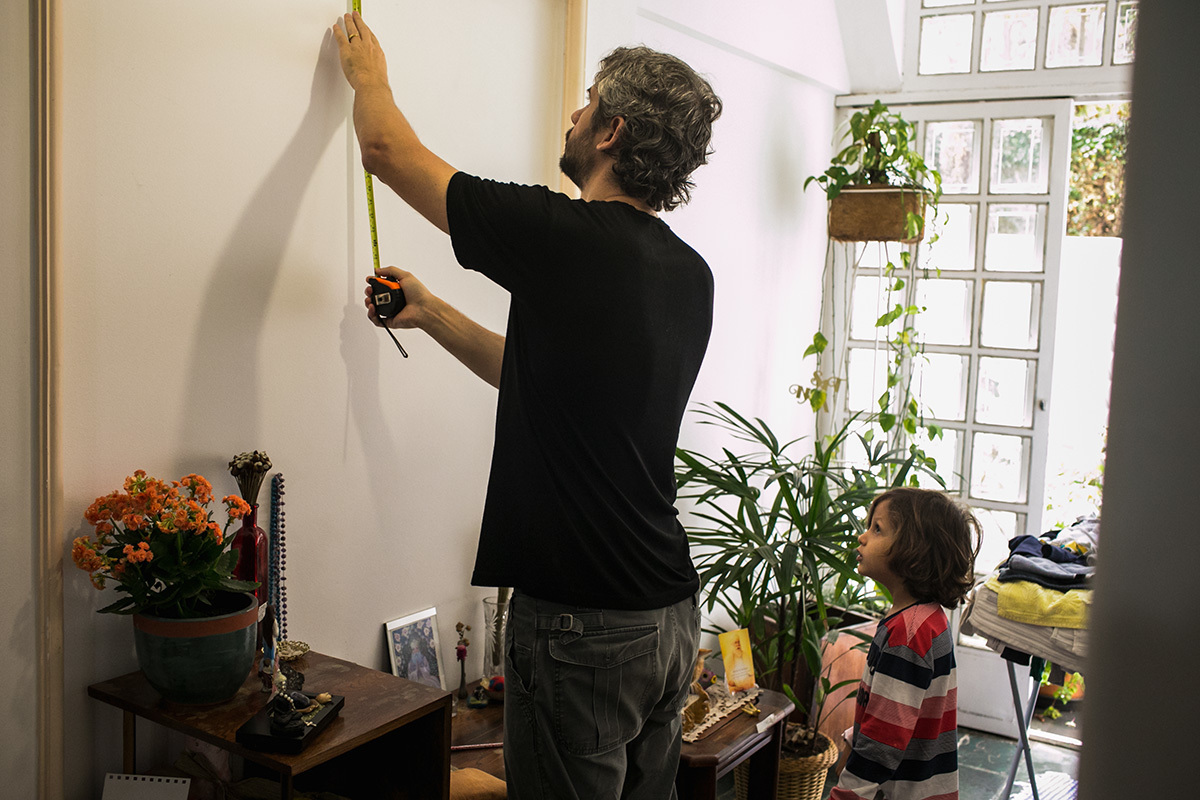 pai e filho tirando a medida da parede para fixar o quadro do artista Rogério Fernandes