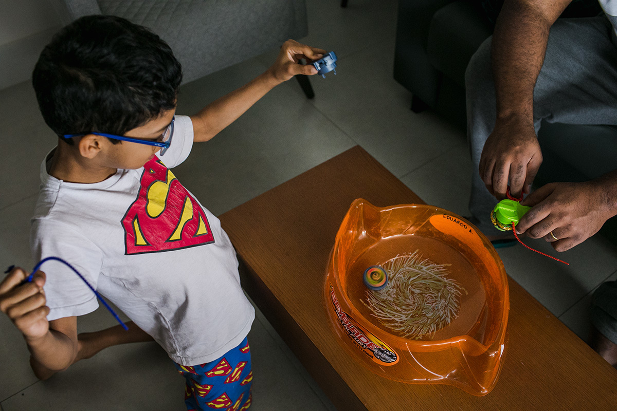 filho joga Beyblade com o pai em foto de Adriana Costa