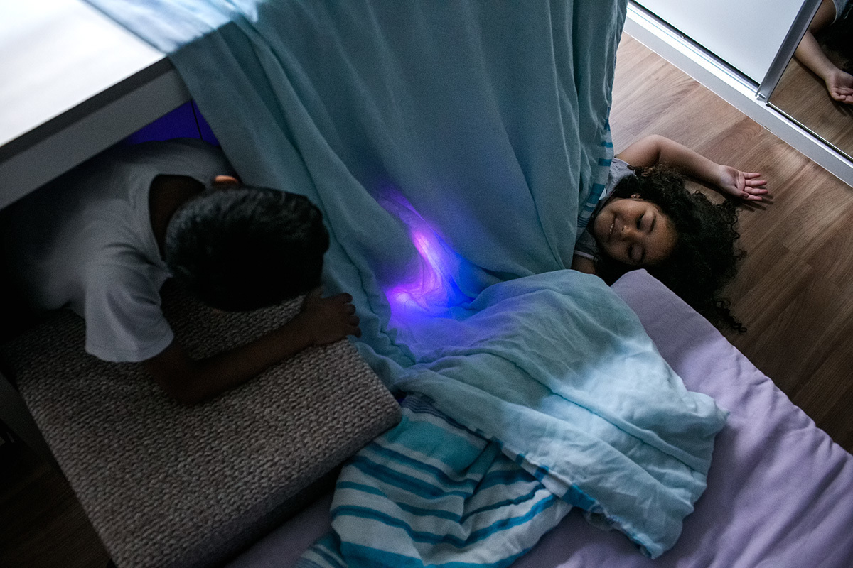 crianças brincando de cabana com lençóis no quarto de dormir, por adrianacostafotos