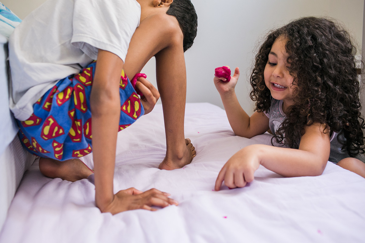 irmãos tentando tirar do lençol a geleca que deixaram grudar nela