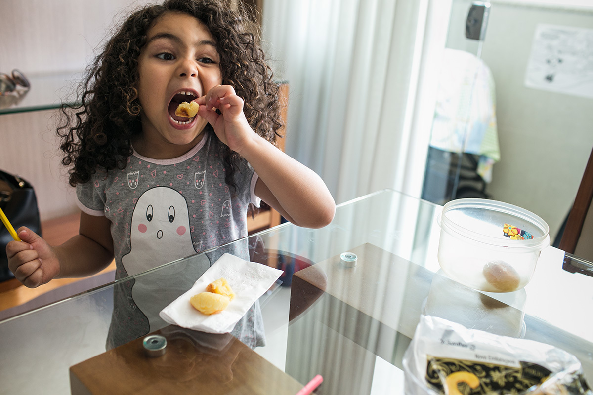 menina fazendo careta para comer o pão de queijo quente