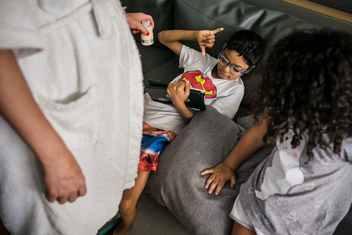 mãe oferecendo yakult para o filho, em foto de Adriana Costa