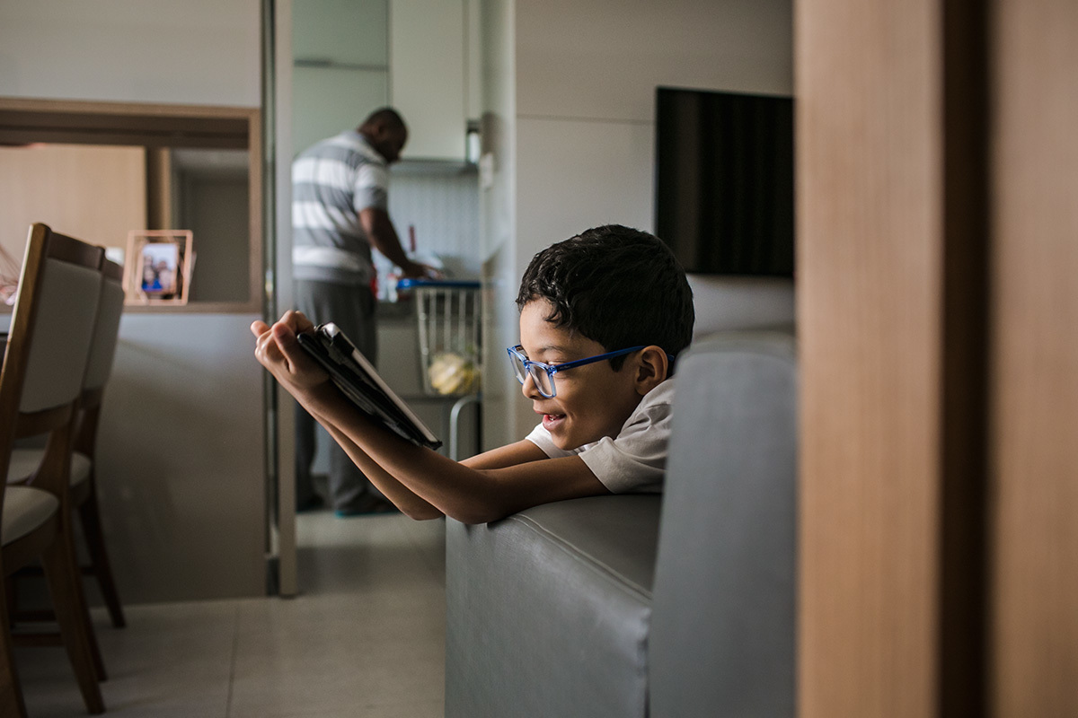 pai guardando compras de supermercado enquanto filho assisti filme no ipad, por Adriana Costa