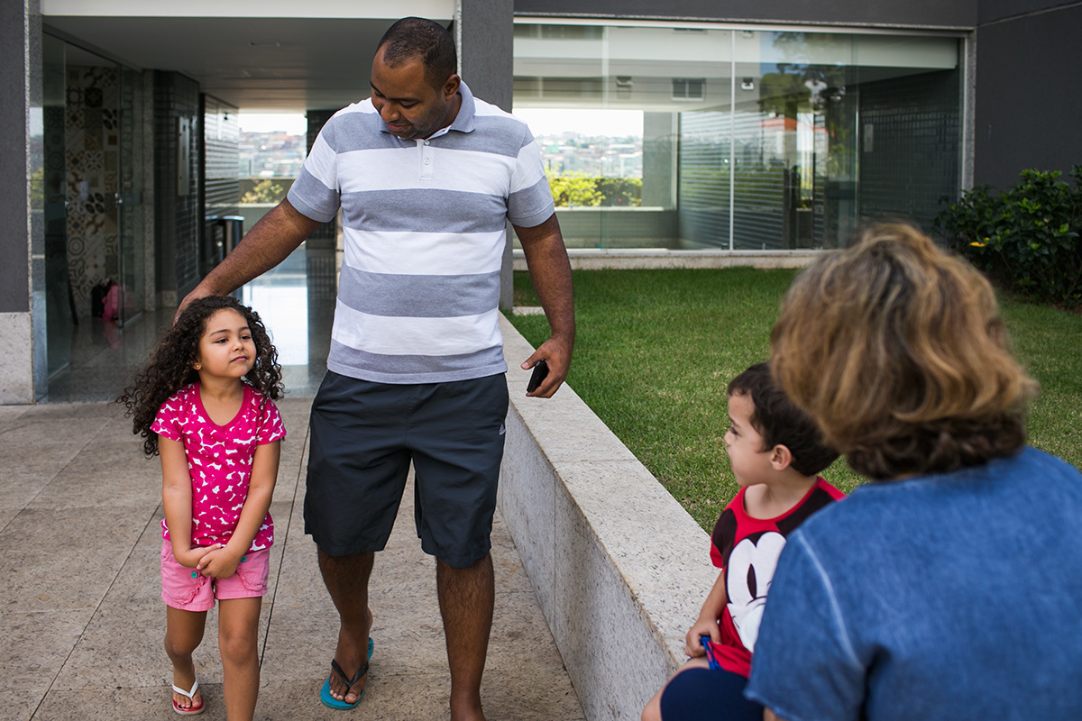 pai levando a filha para brincar com outras crianças no playground do prédio