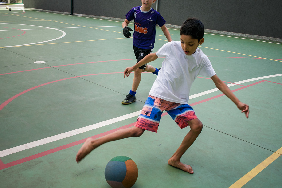 Adriana costa fotografou menino driblando a bola do colega no futebol
