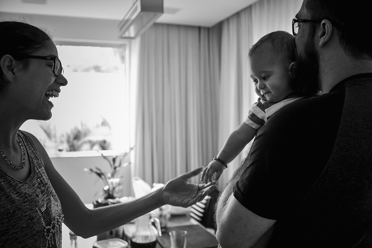 mãe dando a mão ao seu bebê que está no colo do pai