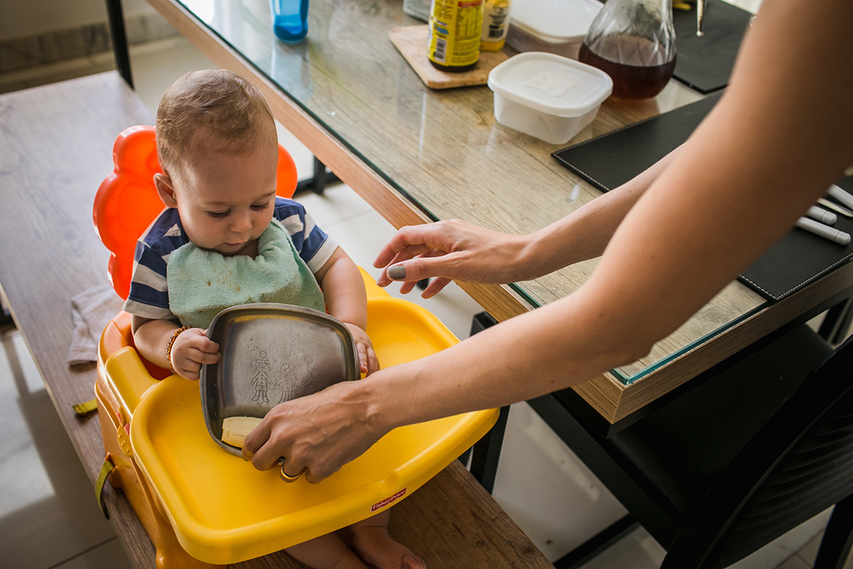 bebê virando o prato com banana que sua mãe acabou de dar, por adrianacostafotos