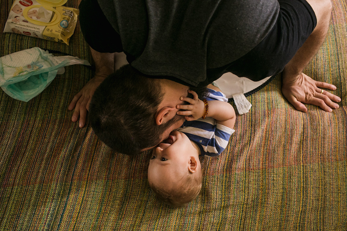 foto de Adriana Costa do pai beijando filho no momento de trocar fralda